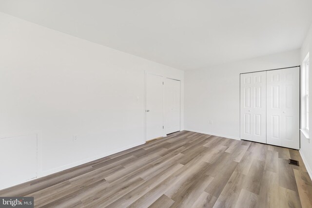 unfurnished bedroom with two closets and light hardwood / wood-style floors