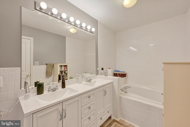 bathroom featuring tiled tub and vanity