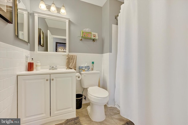 bathroom with tile patterned floors, vanity, toilet, and tile walls