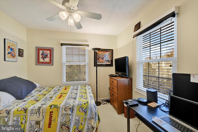 bedroom with a textured ceiling, ceiling fan, and light carpet