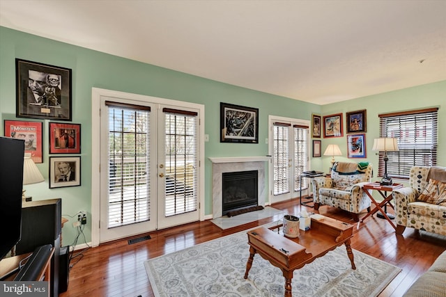 living room with a premium fireplace, french doors, and hardwood / wood-style flooring