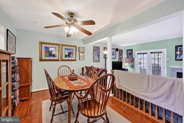 dining space with ceiling fan, french doors, light hardwood / wood-style flooring, decorative columns, and a textured ceiling