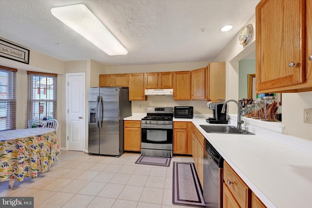 kitchen featuring a textured ceiling, sink, light tile patterned floors, and stainless steel appliances