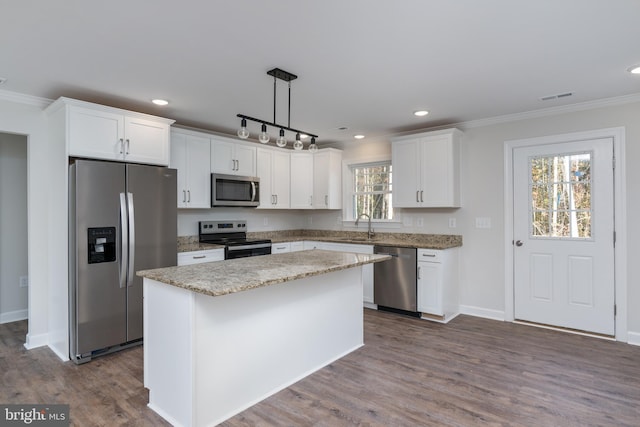 kitchen with stainless steel appliances, plenty of natural light, a kitchen island, white cabinetry, and decorative light fixtures