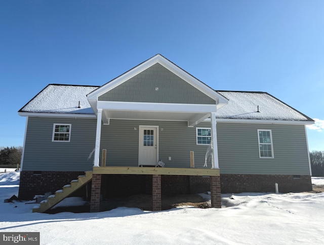 snow covered rear of property with covered porch