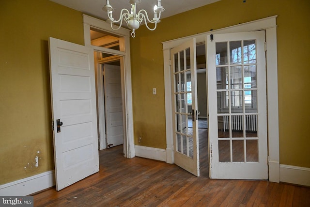 unfurnished room with a chandelier, french doors, and dark hardwood / wood-style floors