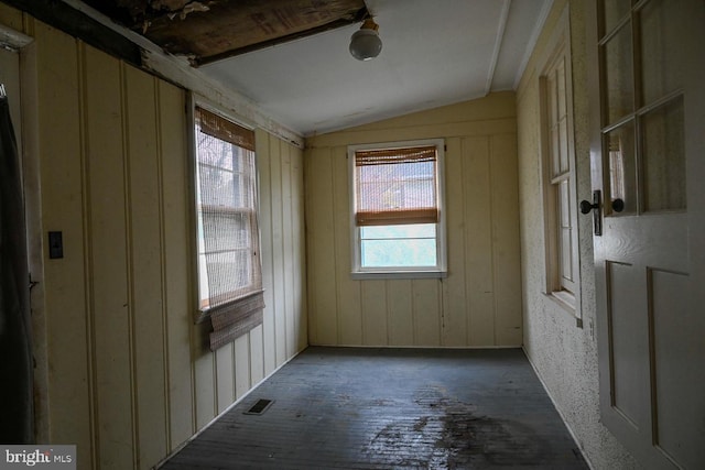 unfurnished room with dark hardwood / wood-style flooring, vaulted ceiling, and wooden walls