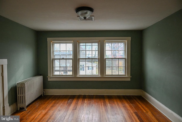 spare room featuring plenty of natural light, dark hardwood / wood-style flooring, and radiator