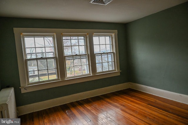 spare room with radiator heating unit and hardwood / wood-style floors