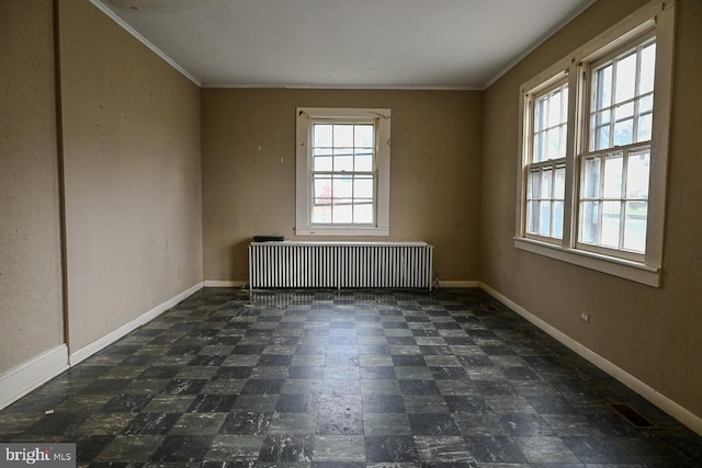 spare room with a wealth of natural light, radiator, and ornamental molding