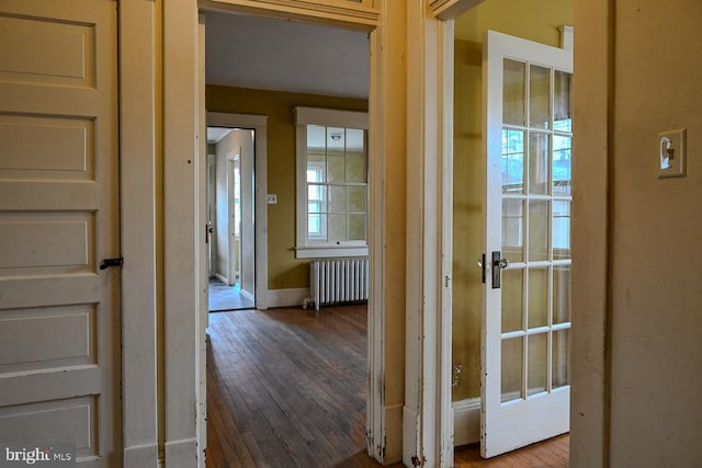 corridor with hardwood / wood-style flooring and radiator heating unit