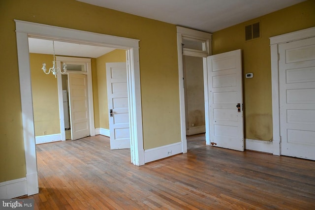 unfurnished room featuring a notable chandelier and wood-type flooring