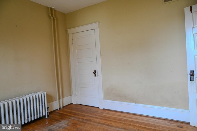 unfurnished room with wood-type flooring and radiator heating unit