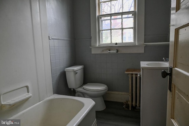 bathroom featuring a tub, radiator, hardwood / wood-style floors, and tile walls