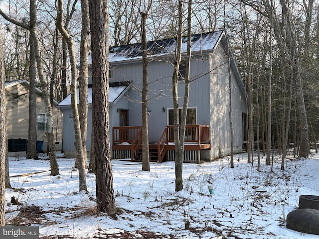 snow covered house featuring a wooden deck