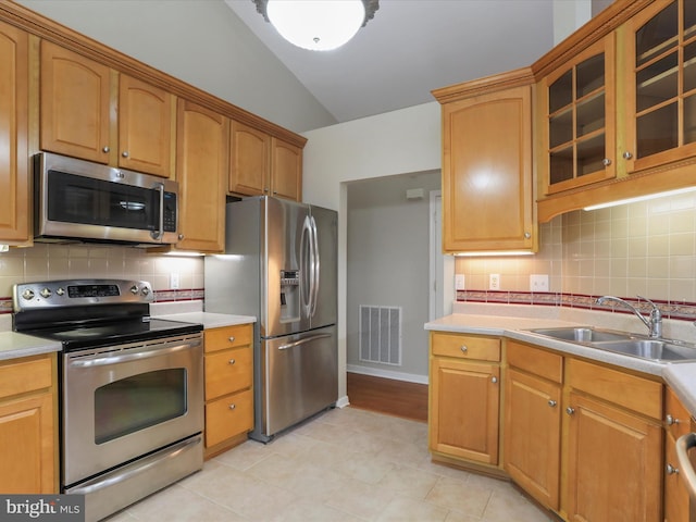 kitchen featuring tasteful backsplash, sink, appliances with stainless steel finishes, and vaulted ceiling