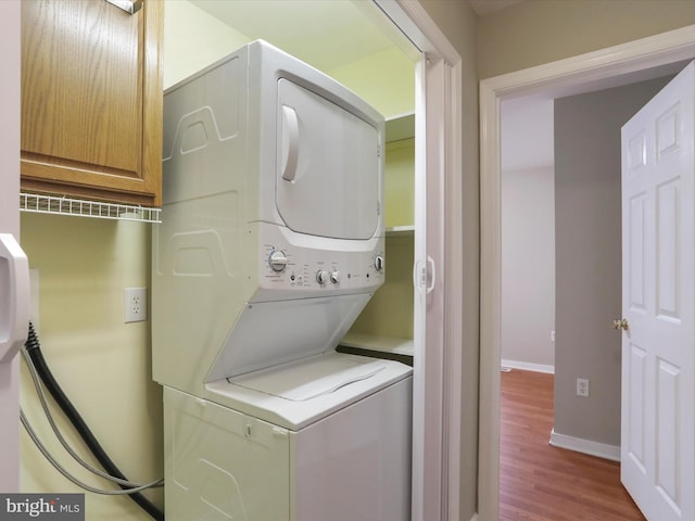 laundry area with hardwood / wood-style floors and stacked washer and dryer