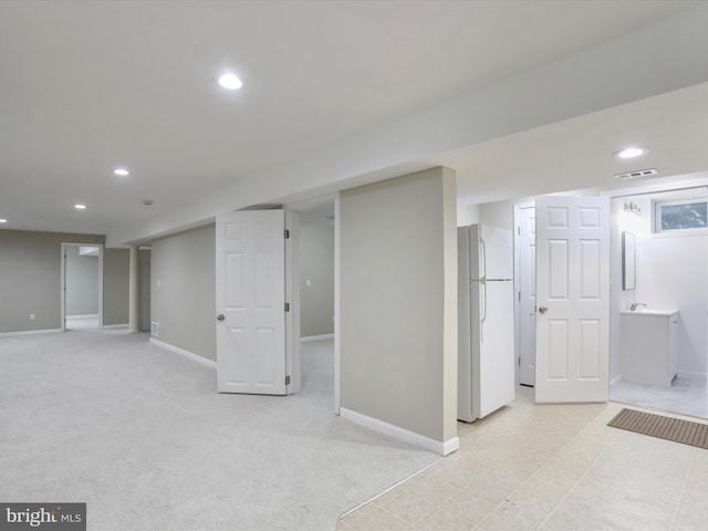 basement with light carpet and white refrigerator