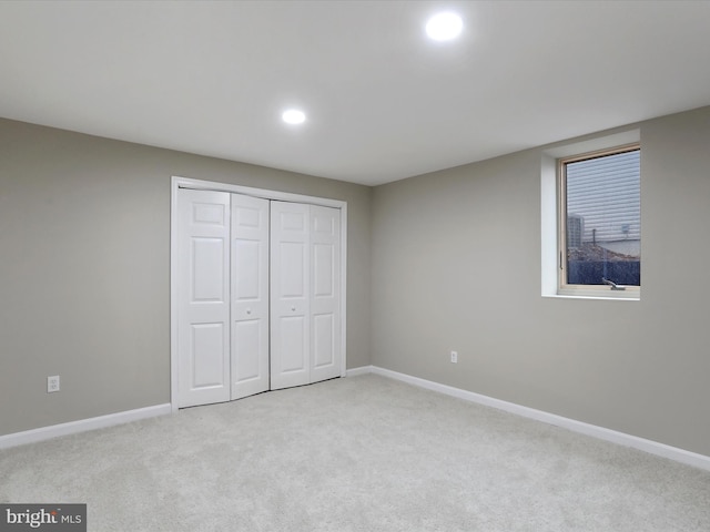 unfurnished bedroom with a closet and light colored carpet