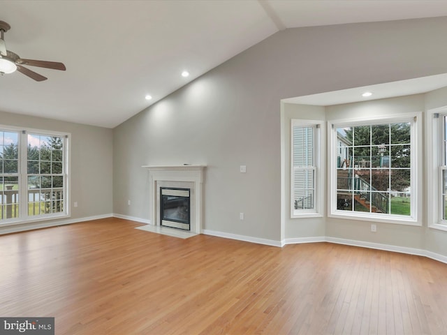 unfurnished living room featuring a fireplace, light wood-type flooring, vaulted ceiling, and ceiling fan