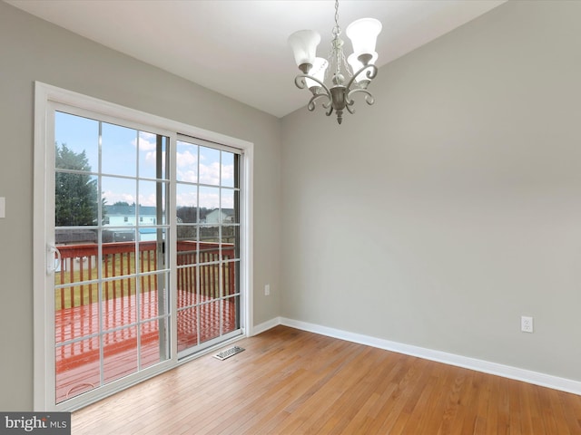 unfurnished dining area featuring wood-type flooring and an inviting chandelier