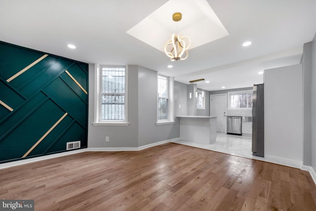 unfurnished living room with light hardwood / wood-style floors and a notable chandelier