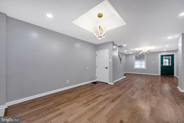 unfurnished living room with light wood-type flooring and an inviting chandelier