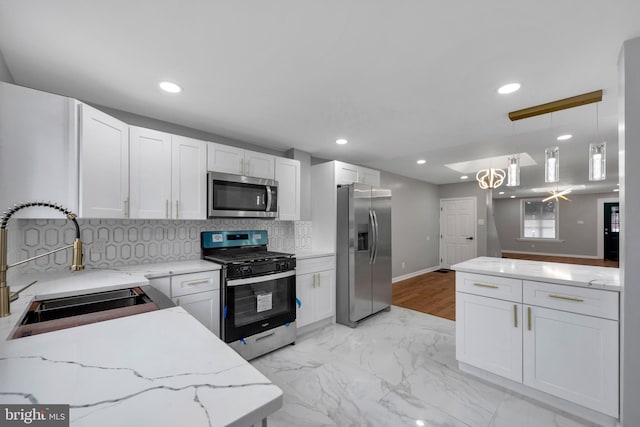 kitchen with white cabinets, decorative light fixtures, sink, and stainless steel appliances