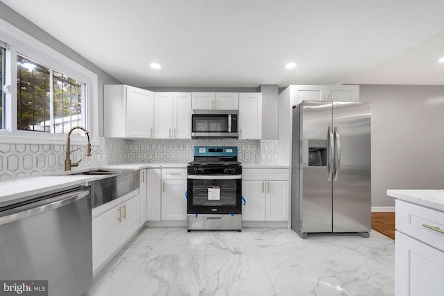 kitchen with backsplash, stainless steel appliances, white cabinetry, and sink