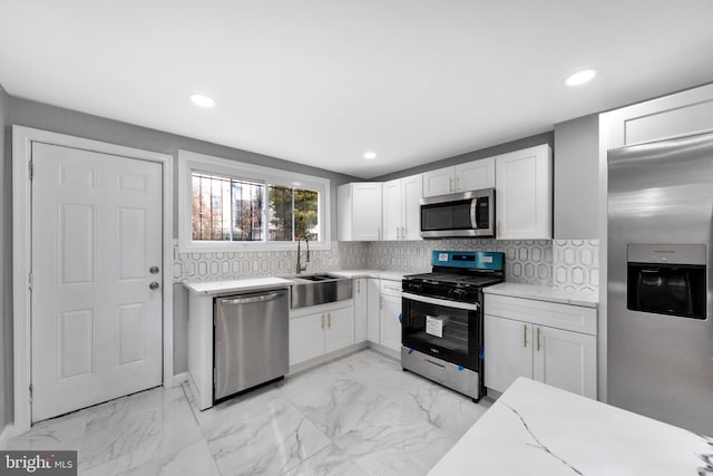 kitchen featuring decorative backsplash, white cabinetry, sink, and stainless steel appliances