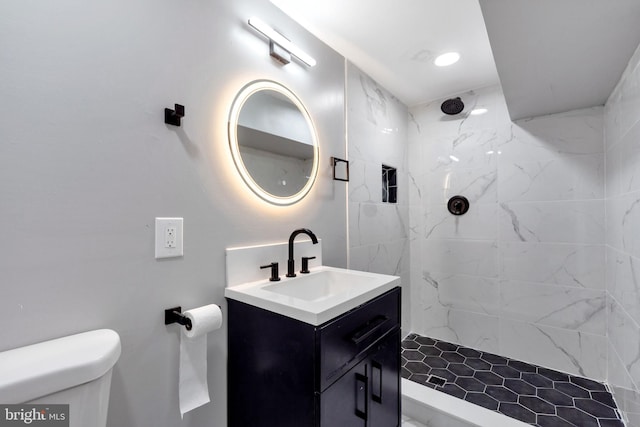 bathroom with vanity, toilet, and a tile shower