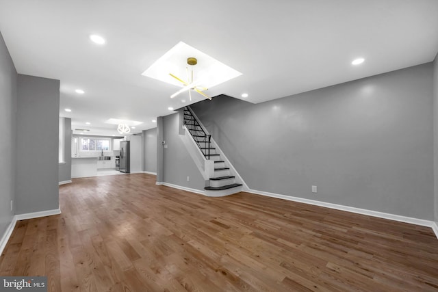 unfurnished living room with wood-type flooring and a notable chandelier