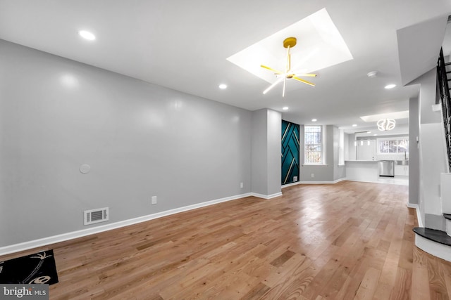 unfurnished living room featuring light wood-type flooring and a chandelier