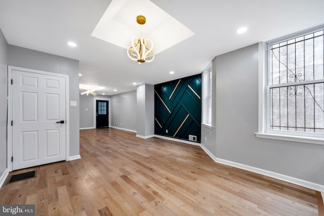 spare room featuring plenty of natural light, light wood-type flooring, and ceiling fan with notable chandelier