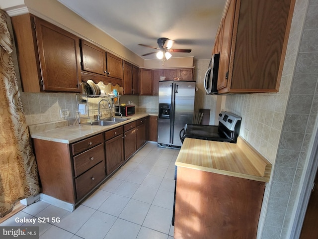 kitchen with sink, ceiling fan, light tile patterned floors, tasteful backsplash, and stainless steel appliances