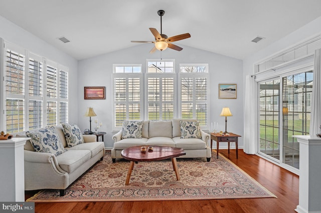 living room with wood-type flooring, vaulted ceiling, and a healthy amount of sunlight