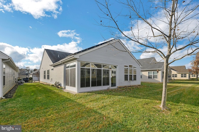 back of property with a yard and a sunroom