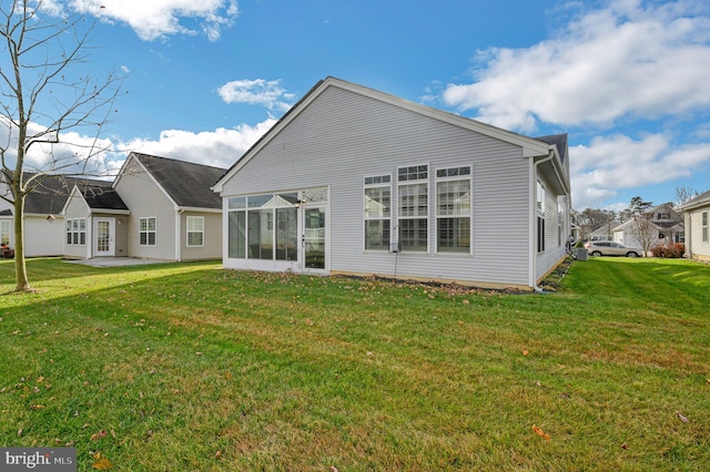 back of property with a yard and a sunroom