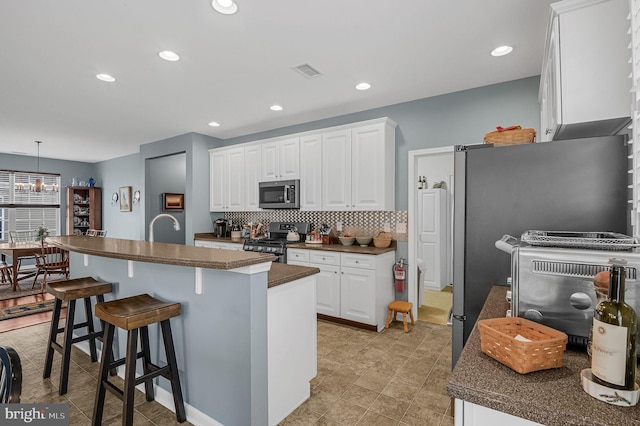 kitchen featuring a center island with sink, white cabinets, decorative backsplash, decorative light fixtures, and stainless steel appliances