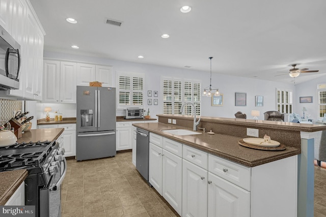 kitchen with white cabinets, sink, an island with sink, decorative light fixtures, and stainless steel appliances