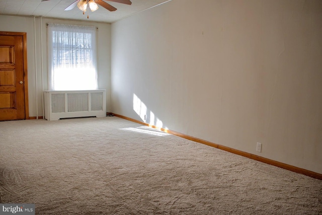 carpeted spare room with ceiling fan, crown molding, and radiator