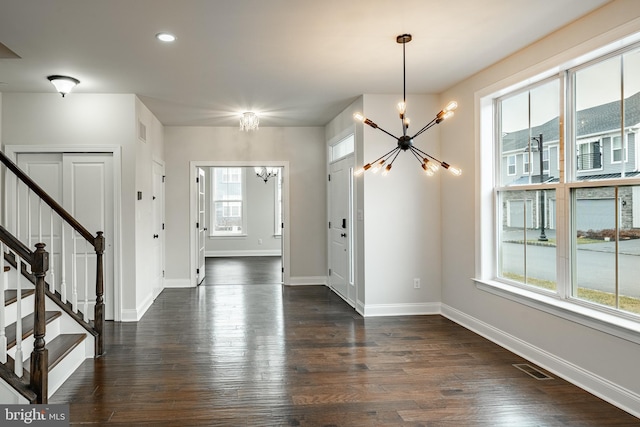 foyer featuring dark wood-type flooring, an inviting chandelier, and a healthy amount of sunlight