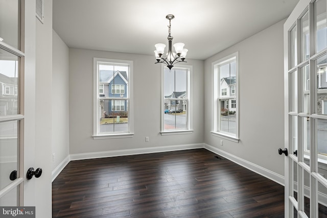 unfurnished dining area with french doors, dark hardwood / wood-style floors, and an inviting chandelier