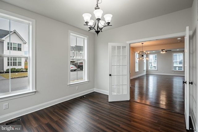 unfurnished dining area featuring french doors, ceiling fan with notable chandelier, and dark hardwood / wood-style floors