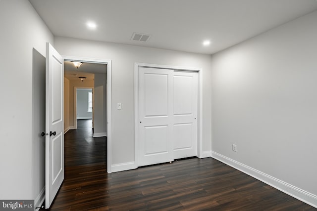 unfurnished bedroom featuring dark hardwood / wood-style floors and a closet