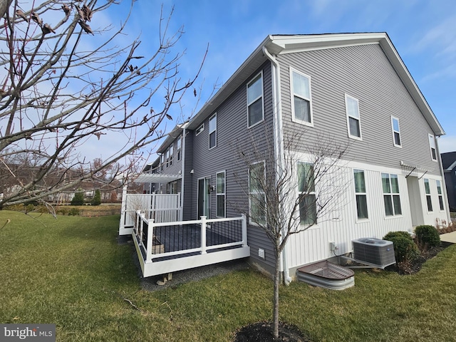 rear view of house featuring a lawn, a wooden deck, and cooling unit