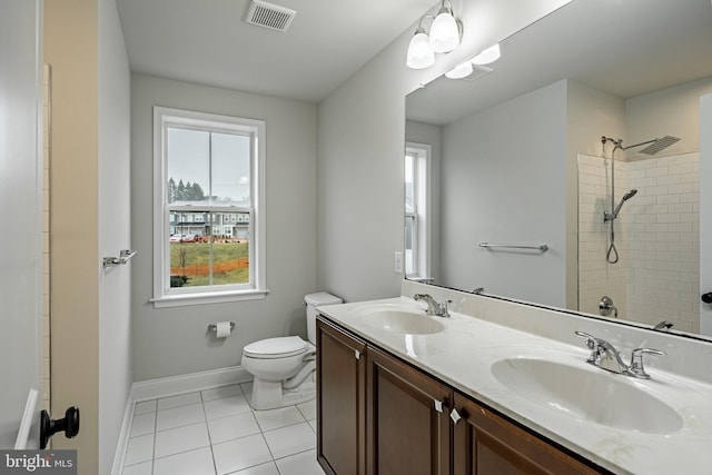 bathroom with tiled shower, tile patterned flooring, vanity, and toilet