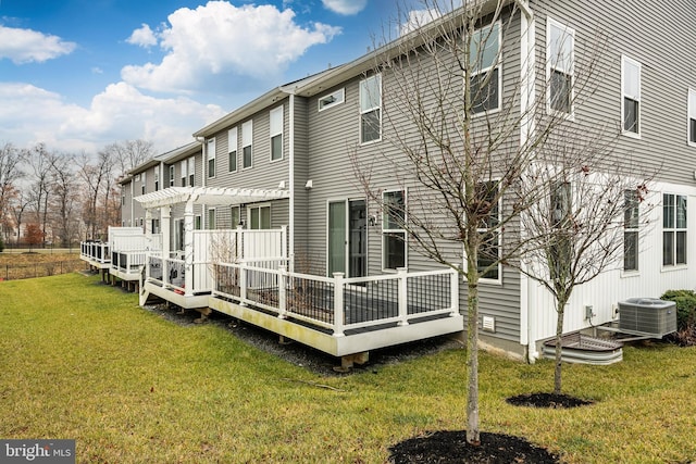 back of property with a pergola, a wooden deck, a yard, and central AC