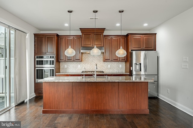 kitchen with decorative light fixtures, an island with sink, stainless steel appliances, and dark hardwood / wood-style floors