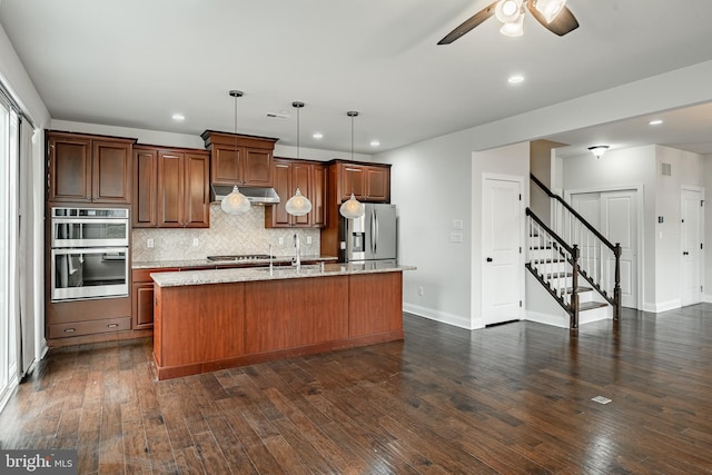 kitchen featuring decorative light fixtures, stainless steel appliances, dark wood-type flooring, and an island with sink